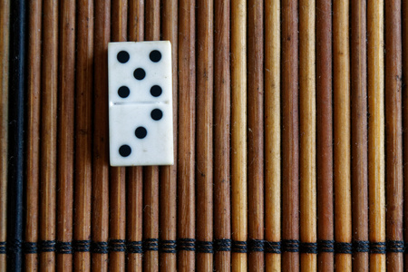 Domino piece on the bamboo brown wooden table background. Domino set - three - 5 dots.の写真素材