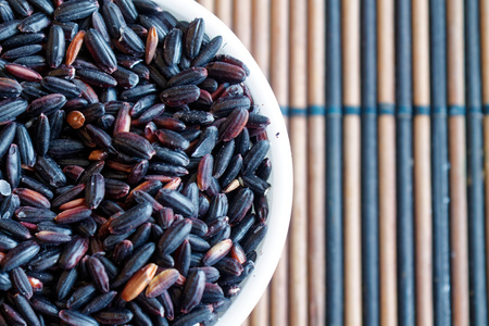 Texture of Coarse black rice in white plate The concept of proper nutrition and healthy lifestyle. Top view, close-up as background or textureの写真素材