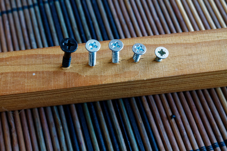 Scattered screws screwed into the wooden plank