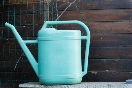 Old blue plastic watering can on wooden backgroundの写真素材