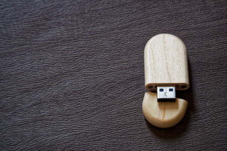 Usb flash drive with wooden surface on desk for USB port plug-in computer laptop for transfer data and backup business concept.の写真素材