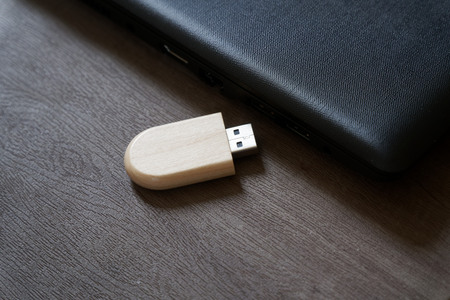 Usb flash drive with wooden surface on desk for USB port plug-in computer laptop for transfer data and backup business concept.の写真素材