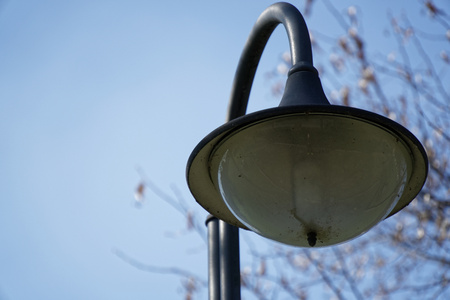 Street lantern in sunny day, turned off, urban background.