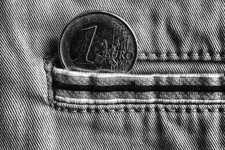 Euro coin with a denomination of one euro in the pocket of beige denim jeans with stripe, monochrome shot.の写真素材