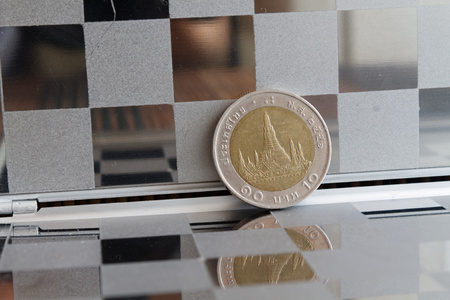 Thai coin in mirror reflect wallet lies on wooden bamboo table background Denomination is ten bahtの写真素材