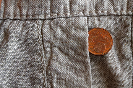 Euro coin with a denomination of one euro cent in the pocket of old linen pants