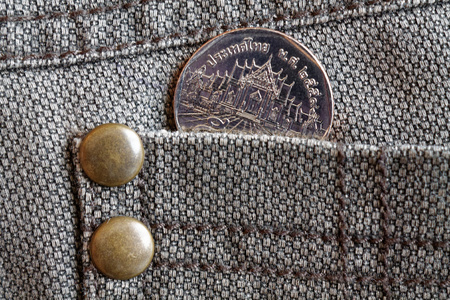 Thai coin with a denomination of five baht in the pocket of brown denim jeans