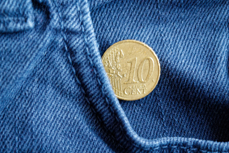 Euro coin with a denomination of ten euro cent in the pocket of worn blue denim jeans