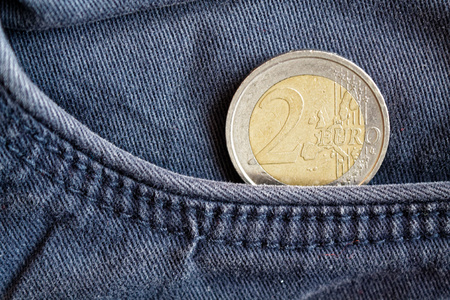 Euro coin with a denomination of two euro in the pocket of old blue denim jeansの写真素材