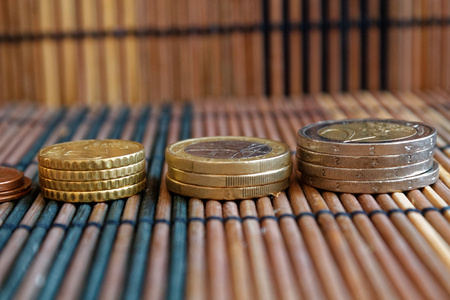 Pile of euro coins, like a tower lies on wooden bamboo table backgroundの写真素材
