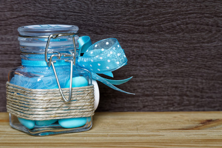 Decorative jar with bow and blue stones inside on wooden table, mockup for postcard or greeting card.の写真素材