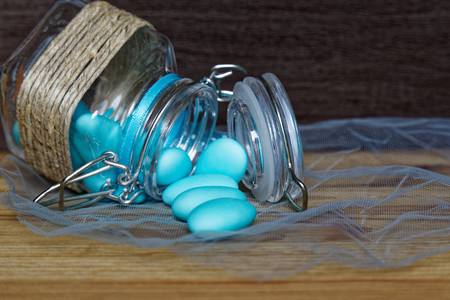 Decorative jar with bow and blue stones inside on wooden table, mockup for postcard or greeting card.の写真素材