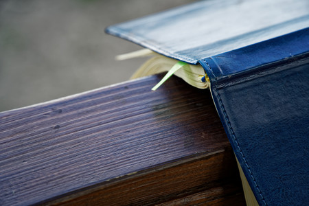 Wind turns the pages of open Notebook lies on wooden handrail in park, business concept.