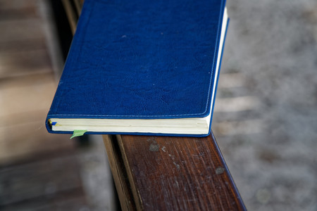 Blue Notebook lies on wooden handrail in park, business concept.