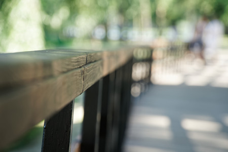 Wooden handrail in Public park with lawn bench and green tree, place for relaxationの写真素材