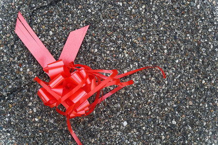 Red bow lies on asphalt, concept of lost hopeの写真素材