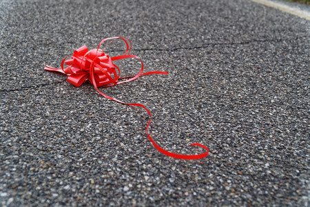 Red bow lies on asphalt, concept of lost hopeの写真素材