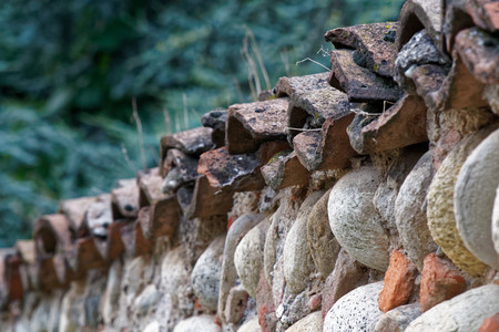 Old roof tiles on stone fence, ruin background