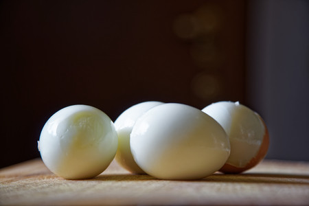 Hard boiled eggs with shell beside on wooden board (Selective Focus, Focus on the front of the shell...