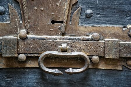 Old wooden door with metal knob and rusty medieval boltの写真素材
