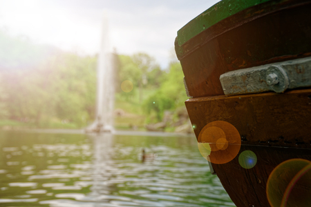 Old wooden boat stern on river and fountain behind.の写真素材