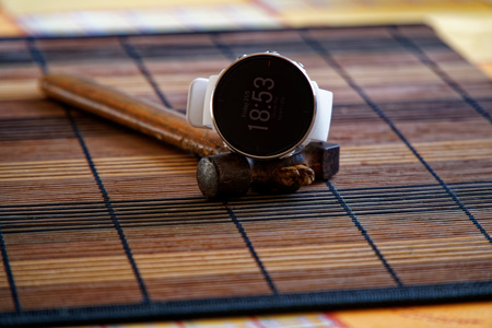 Sport watch in white color on wooden table, Smart watch for running and fitness training. Hammer with wooden handle on background.の写真素材