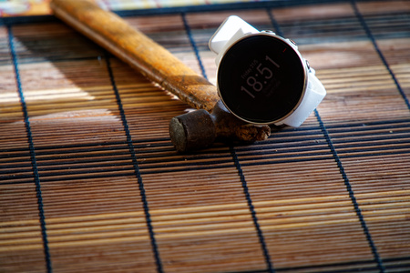 Sport watch in white color on wooden table, Smart watch for running and fitness training. Hammer with wooden handle on background.の写真素材