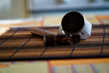 Sport watch in white color on wooden table, Smart watch for running and fitness training. Hammer with wooden handle on background.の写真素材