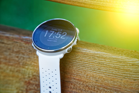 Sport watch for running white color on wooden bench. Fitness watch for tracking daily activity and power trainingの写真素材