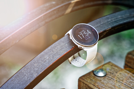 Sport watch for running white color on wooden bench. Fitness watch for tracking daily activity and power trainingの写真素材