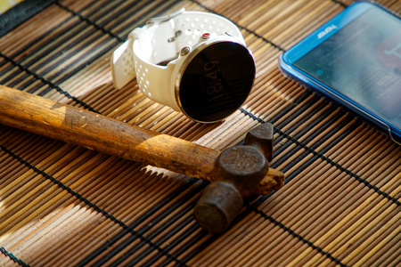 Sport watch in white color on wooden table, Smart watch for running and fitness training. Hammer with wooden handle on background.の写真素材