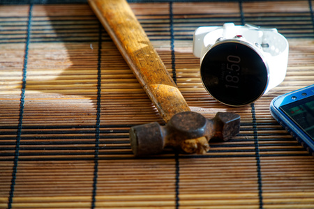 Sport watch in white color on wooden table, Smart watch for running and fitness training. Hammer with wooden handle on background.の写真素材