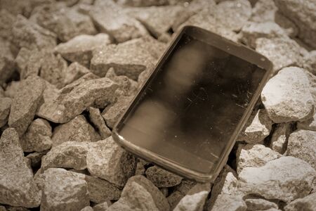 Broken cellphone abandoned and lost among the gravel.の写真素材