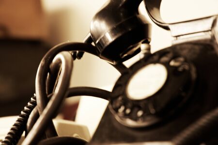 Black retro phone on blurry background. Still life of retro office, telephone on wooden table.の写真素材