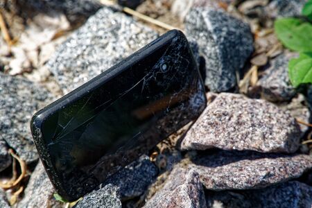 Broken cellphone abandoned and lost among the gravel.の写真素材