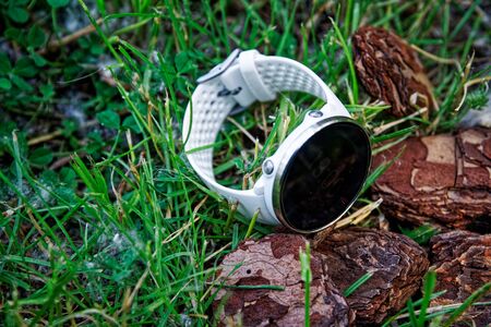 Sport watch for running white color on the ground in the grass. Fitness watch for tracking daily activity and strength training