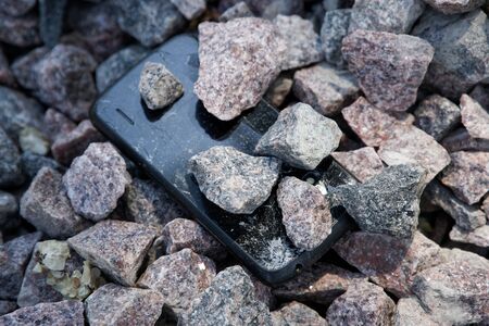 Cell phone with broken glass on gravel granite stones, unbreakable gadget.の写真素材
