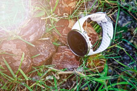 Sport watch for running white color on the ground in the grass. Fitness watch for tracking daily activity and strength trainingの写真素材
