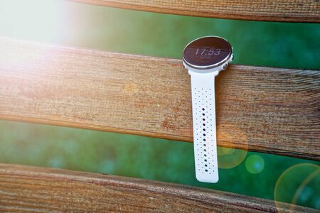 Sport watch for running white color on wooden bench. Fitness watch for tracking daily activity and power trainingの写真素材