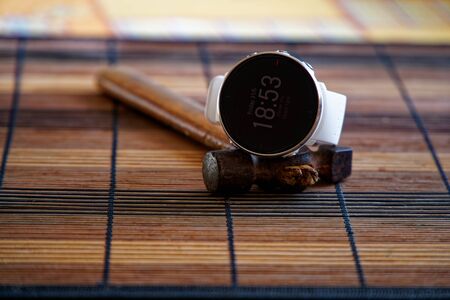 Sport watch in white color on wooden table, Smart watch for running and fitness training. Hammer with wooden handle on background.の写真素材