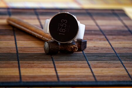 Sport watch in white color on wooden table, Smart watch for running and fitness training. Hammer with wooden handle on background.