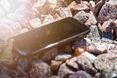 Broken cellphone abandoned and lost among the gravel.の写真素材