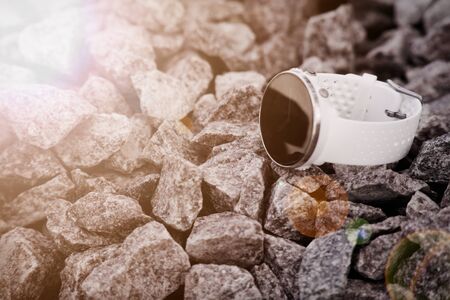 Sport watch for triathlon on the granite gravel. Smart watch for tracking daily activity and strength training. Sun beam lights.の写真素材