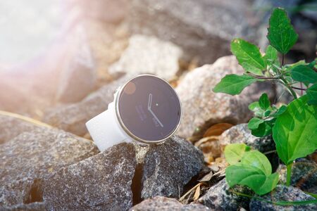 Sport watch for triathlon on the granite gravel. Smart watch for tracking daily activity and strength training. Sun beam lights.の写真素材