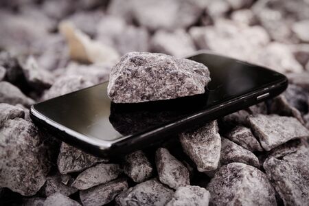 Cell phone with broken glass on gravel granite stones, unbreakable gadget.の写真素材