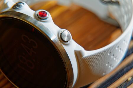 Sport watch in white color and red button on wooden table, Smart watch for running and fitness trainingの写真素材