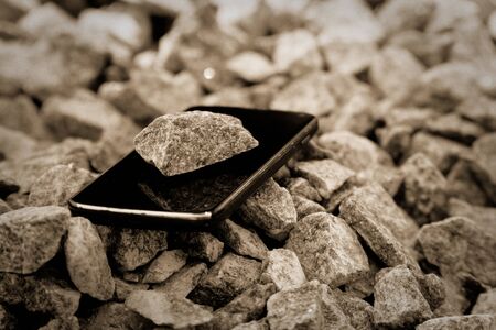 Cell phone with broken glass on gravel granite stones, unbreakable gadget.の写真素材