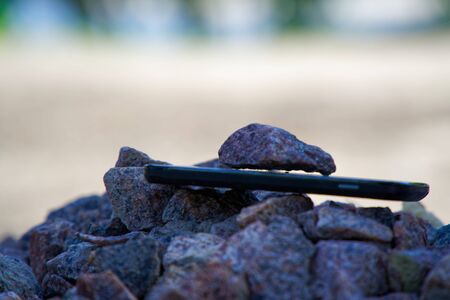 Cell phone with broken glass on gravel granite stones, unbreakable gadget.の写真素材