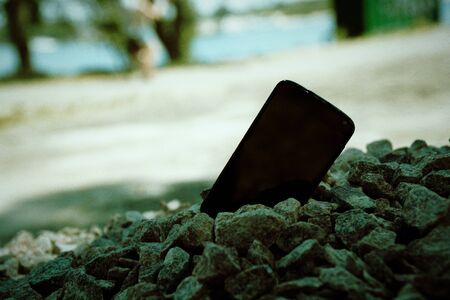Broken cellphone abandoned and lost among the gravel.の写真素材