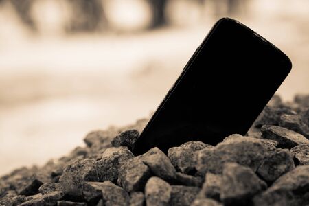 Broken cellphone abandoned and lost among the gravel.の写真素材